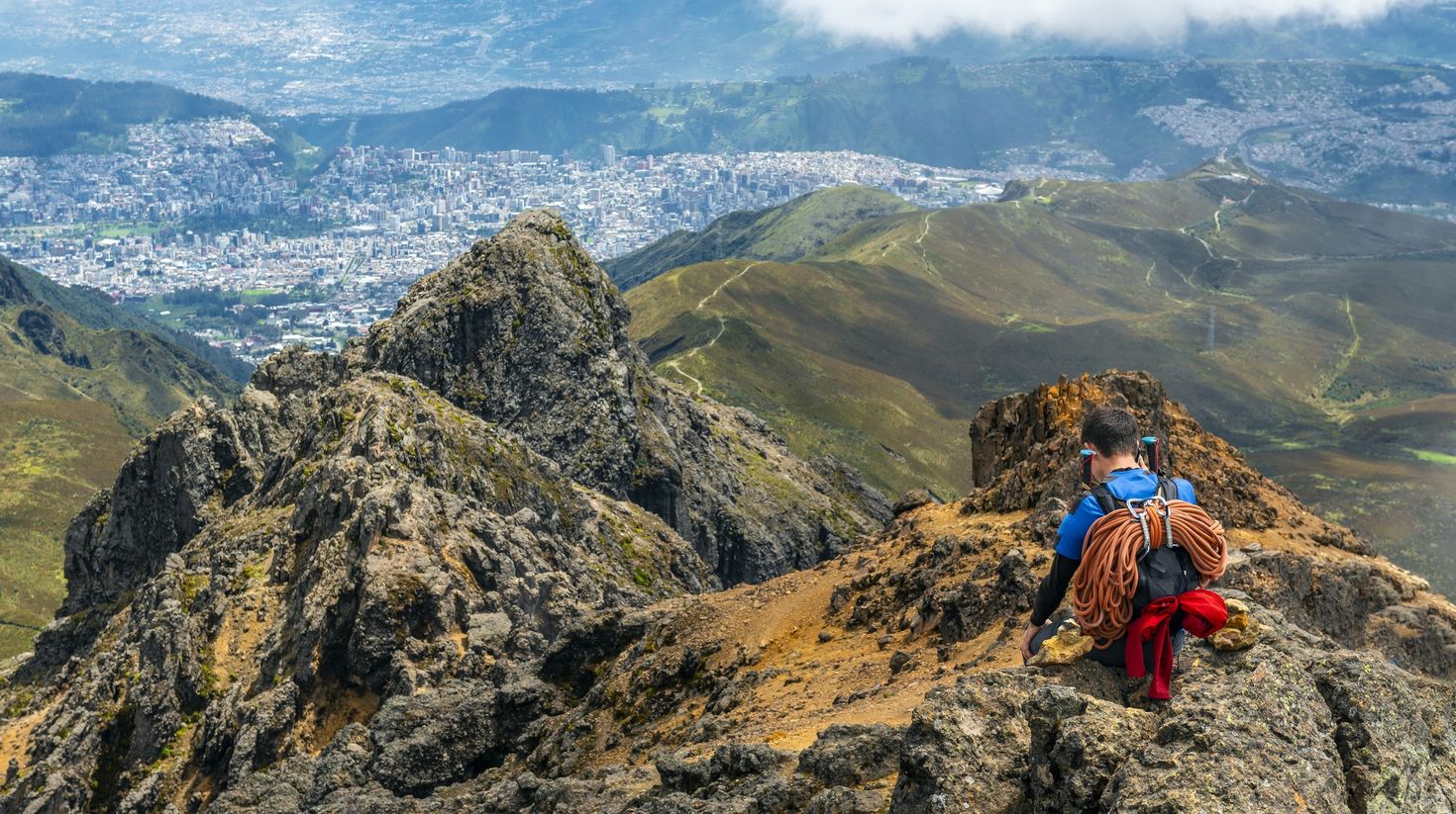 A tourist hiking in Pichincha volcano with Quito city in the background.