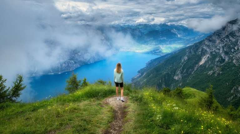 A girl admiring the beauty of Lake Grada during her 12 days in Europe trip.