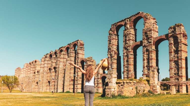 A happy girl in front of Roman Bridge aqueduct during her 5 days in Europe trip.