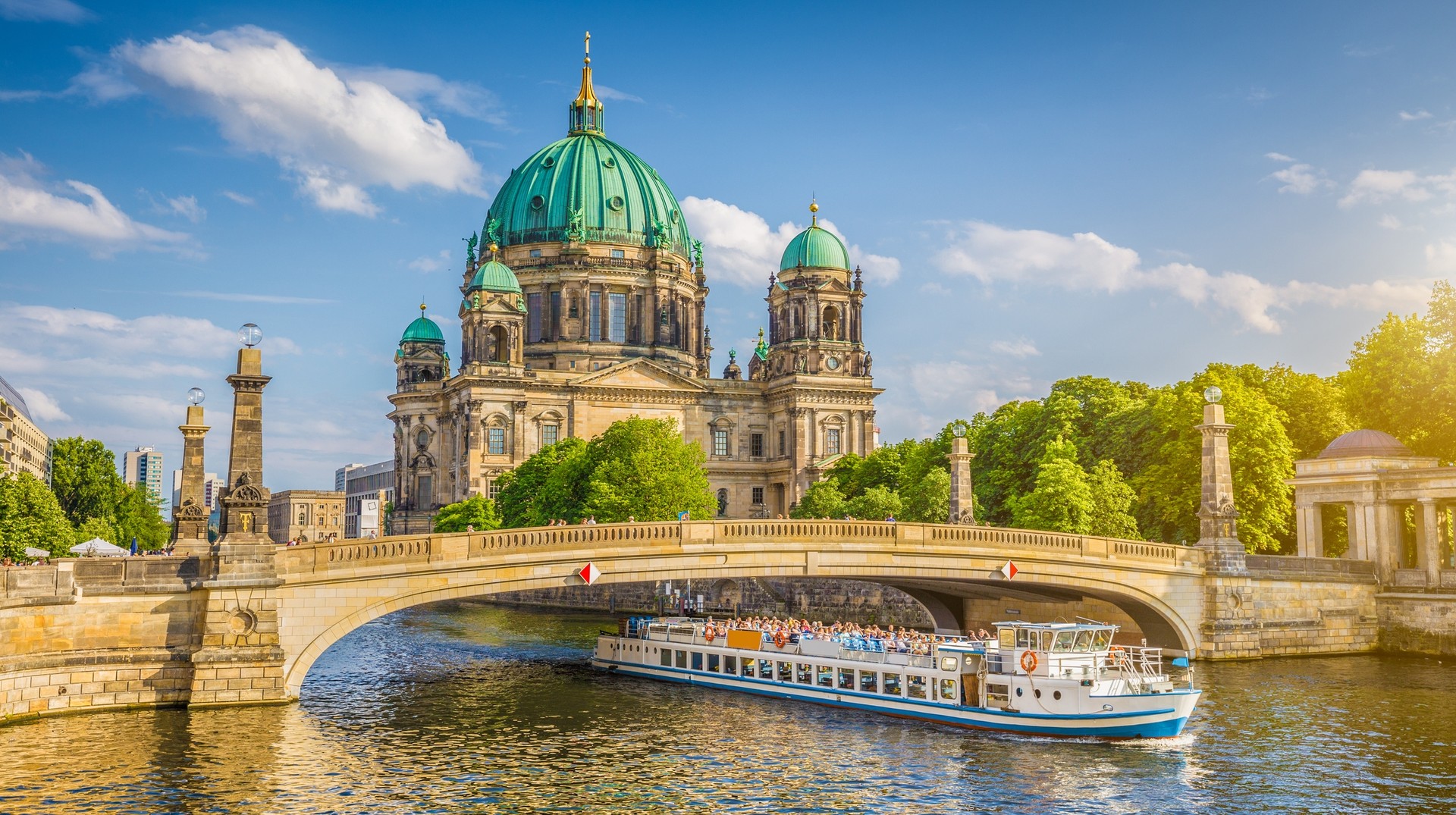 Explore the urban attractions of Berlin while you travel to Germany in April. Berlin Cathedral with ship on Spree river at sunset at Berlin in Germany in April.