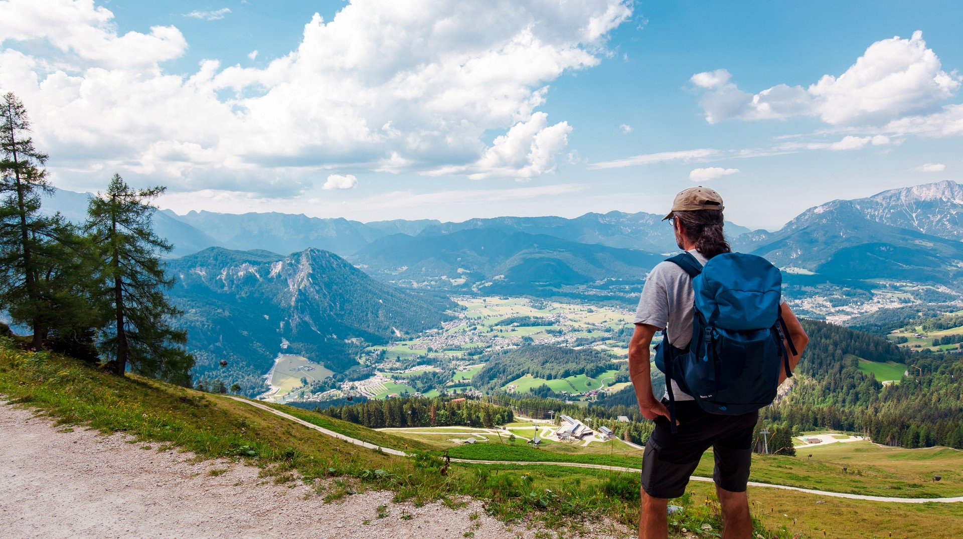Find peace and adventure hiking the Bavarian Alps when you travel to Germany in August. A hiker in the Bavarian Alps on a sunny day in Germany in August.
