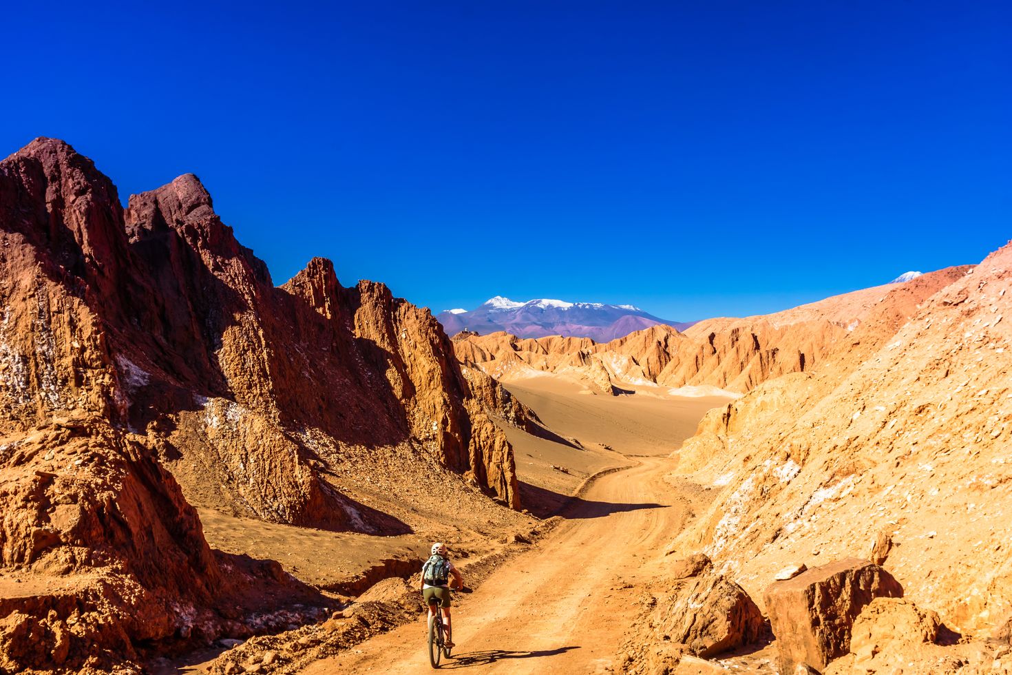 A traveler cycles on a stretch of road between two rocky formations