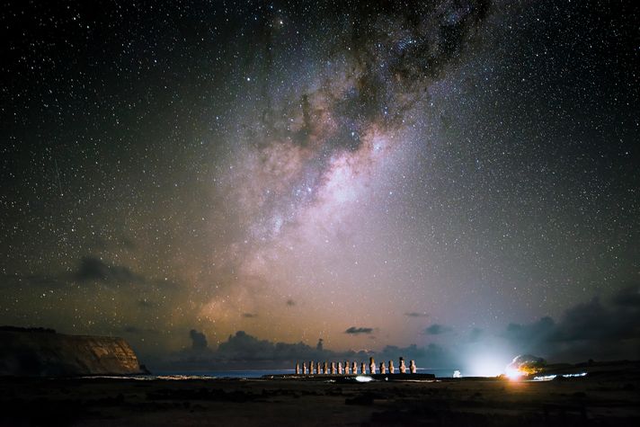 The moai statues stand against the Pacific ocean under the starry nightsky