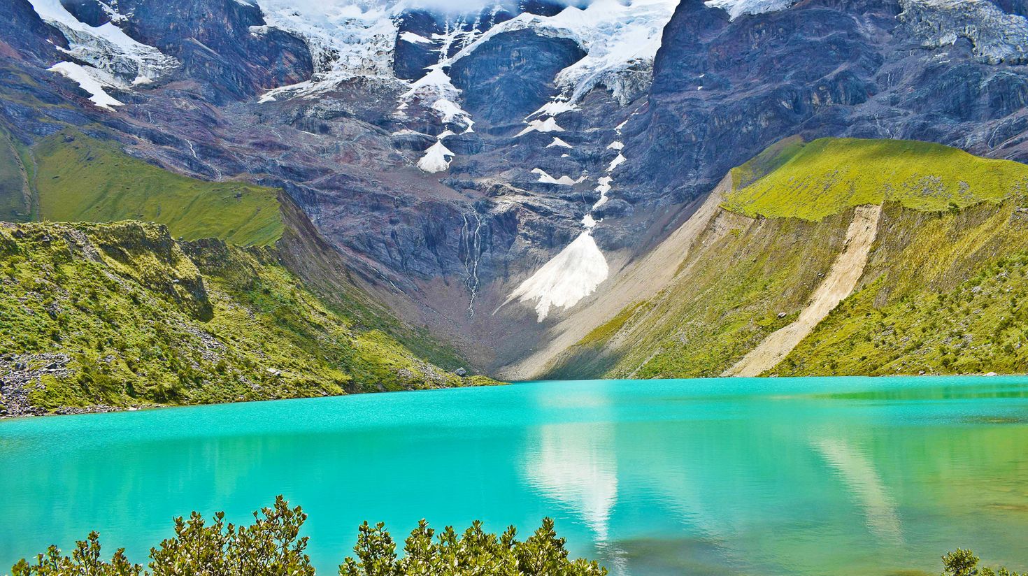 A view of turquoise-colored lake surrounded with hills and mountains