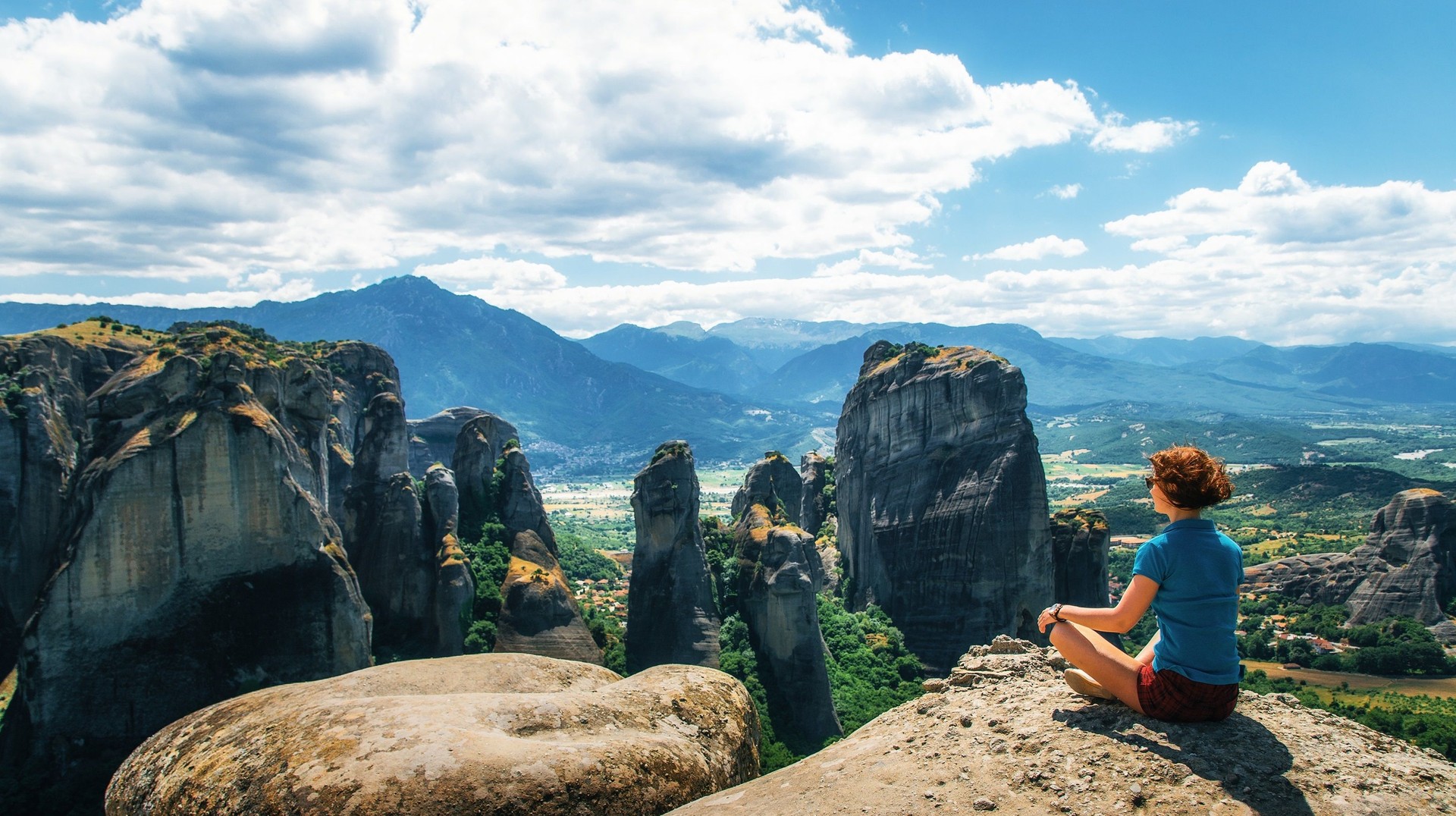 Explore Meteora during your 10 days in Greece and marvel at the awe-inspiring monasteries perched atop towering rock formations A tourist girl sitting and admiring the beauty of Meteora during her 10 days in Greece.