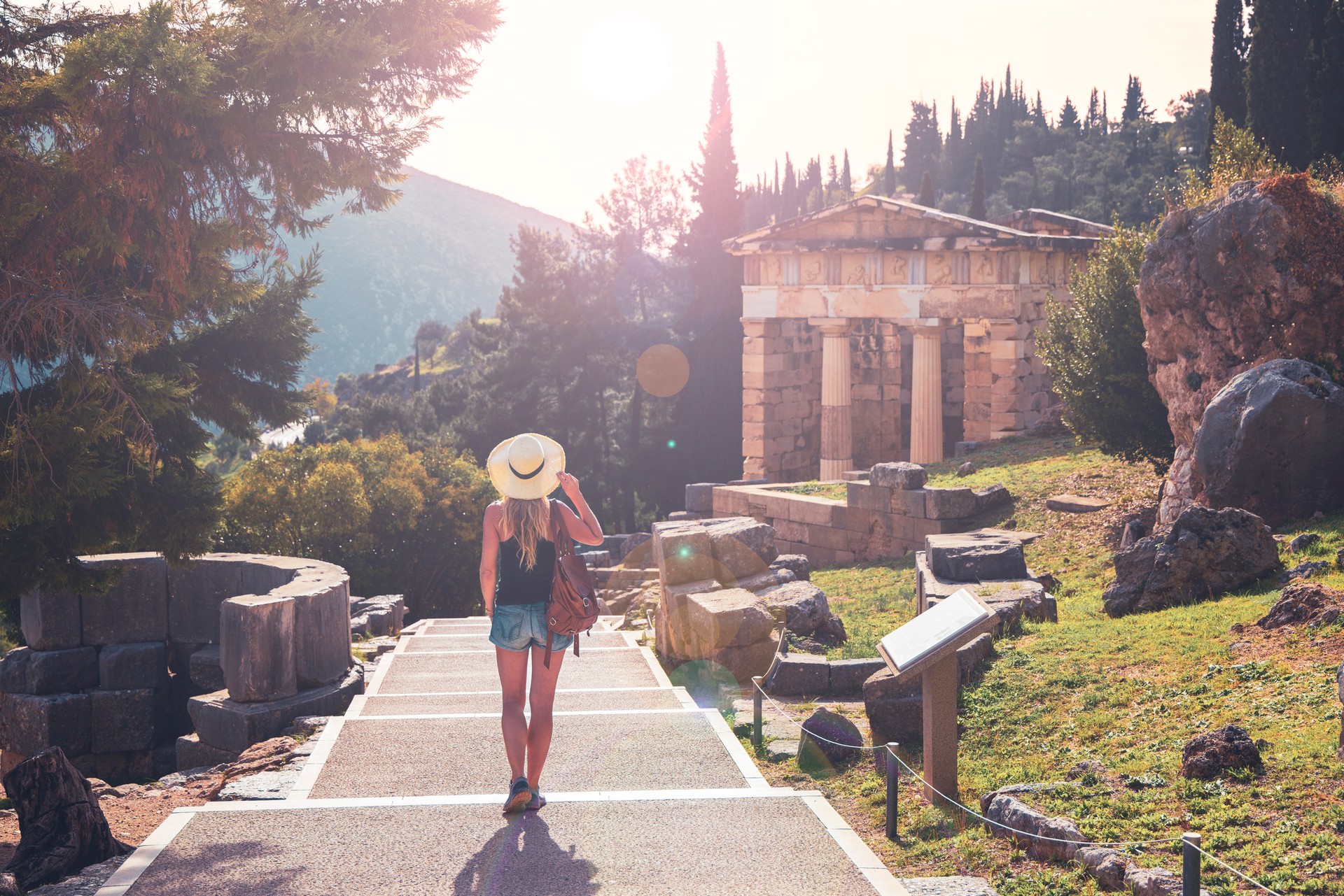 Uncover the mystical charm of Delphi during your 11 days in Greece, where ancient ruins and stunning mountain views bring the legendary history of this sacred site t A tourist walking during sunset in Delphi during her 11 days in Greece.