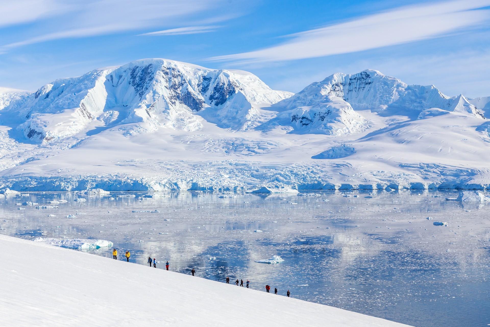 A group of people hiking in Antarctica in the snowy mountains.