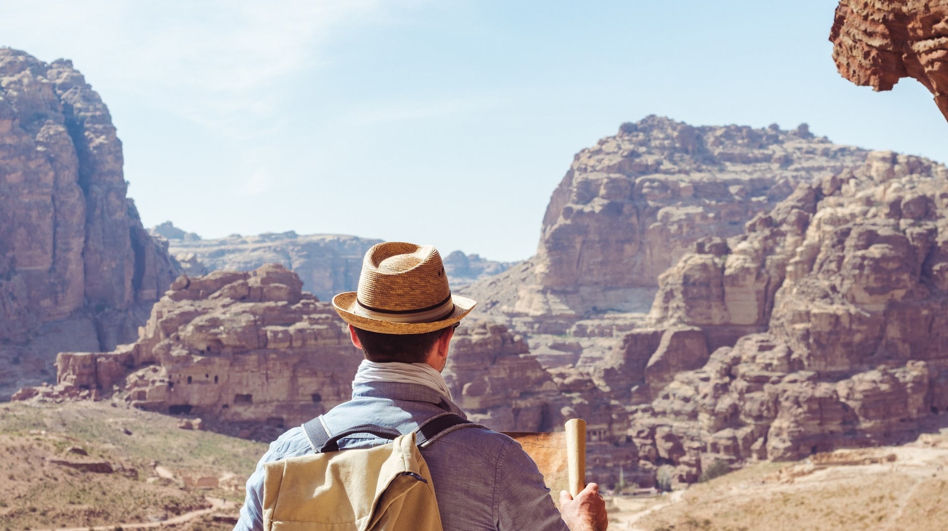 Hiking in Jordan is one of the best experiences as you will take in the country's desert landscapes and iconic historical sites. A hiker hiking in Jordan holding a map in his hand.