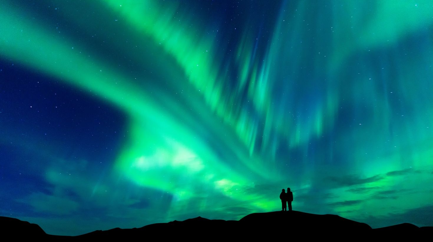 Silhouette of a couple staring at the Aurora borealis in Iceland.