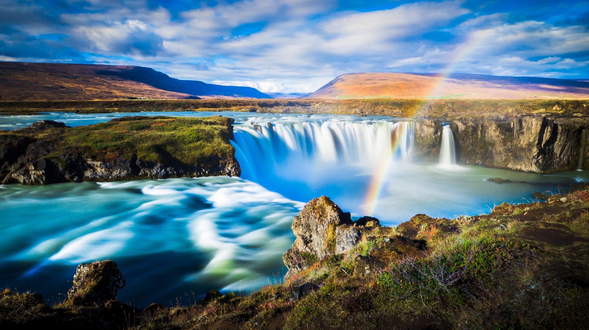 Dramatic long-exposure wide-angle panorama of stunning Godafoss waterfall: Iceland Travel Guide.