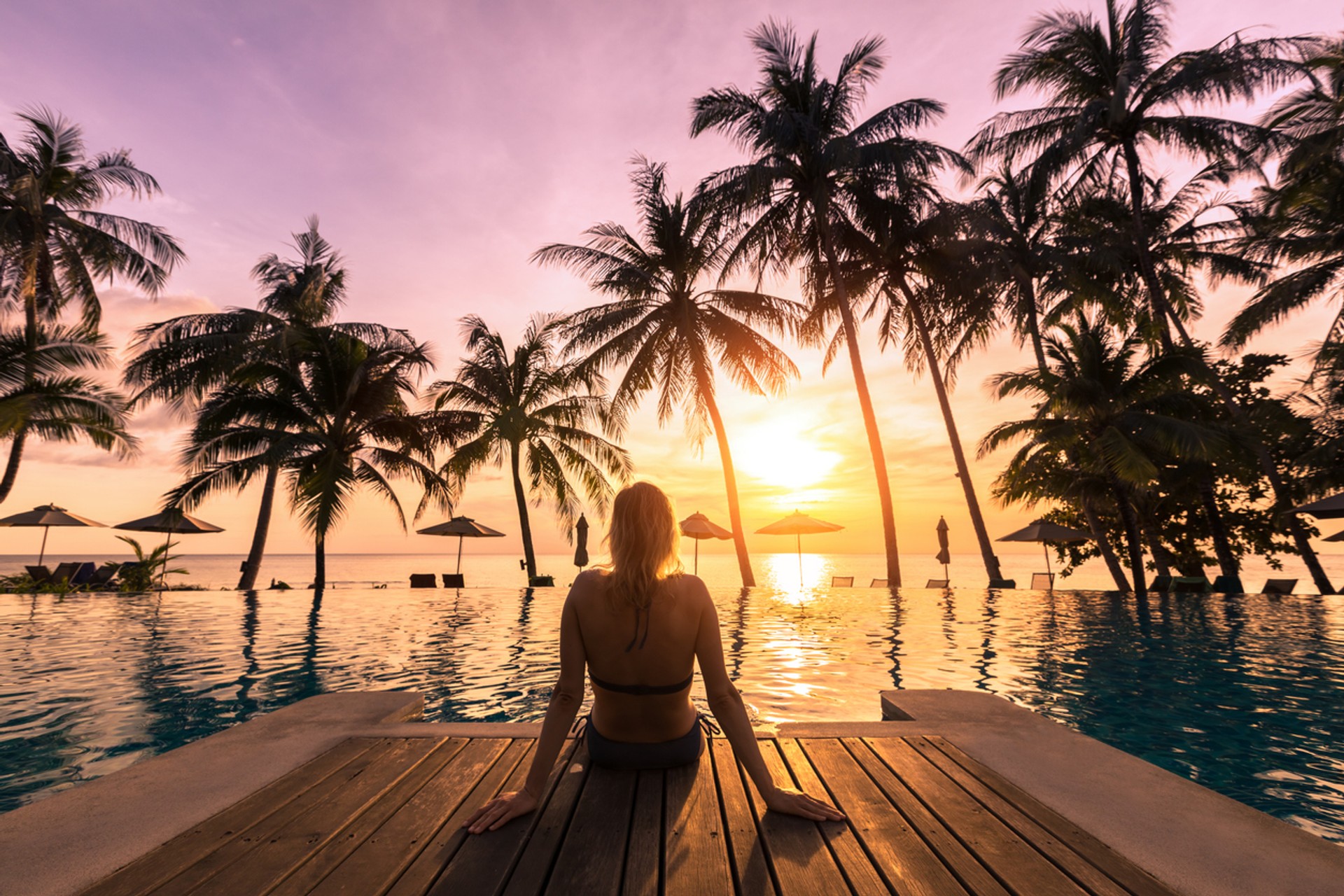 Experience exotic and aesthetic resorts on your tour in Indonesia during the month of April A woman sitting on a deck in an Indonesian resort looking at the sunset