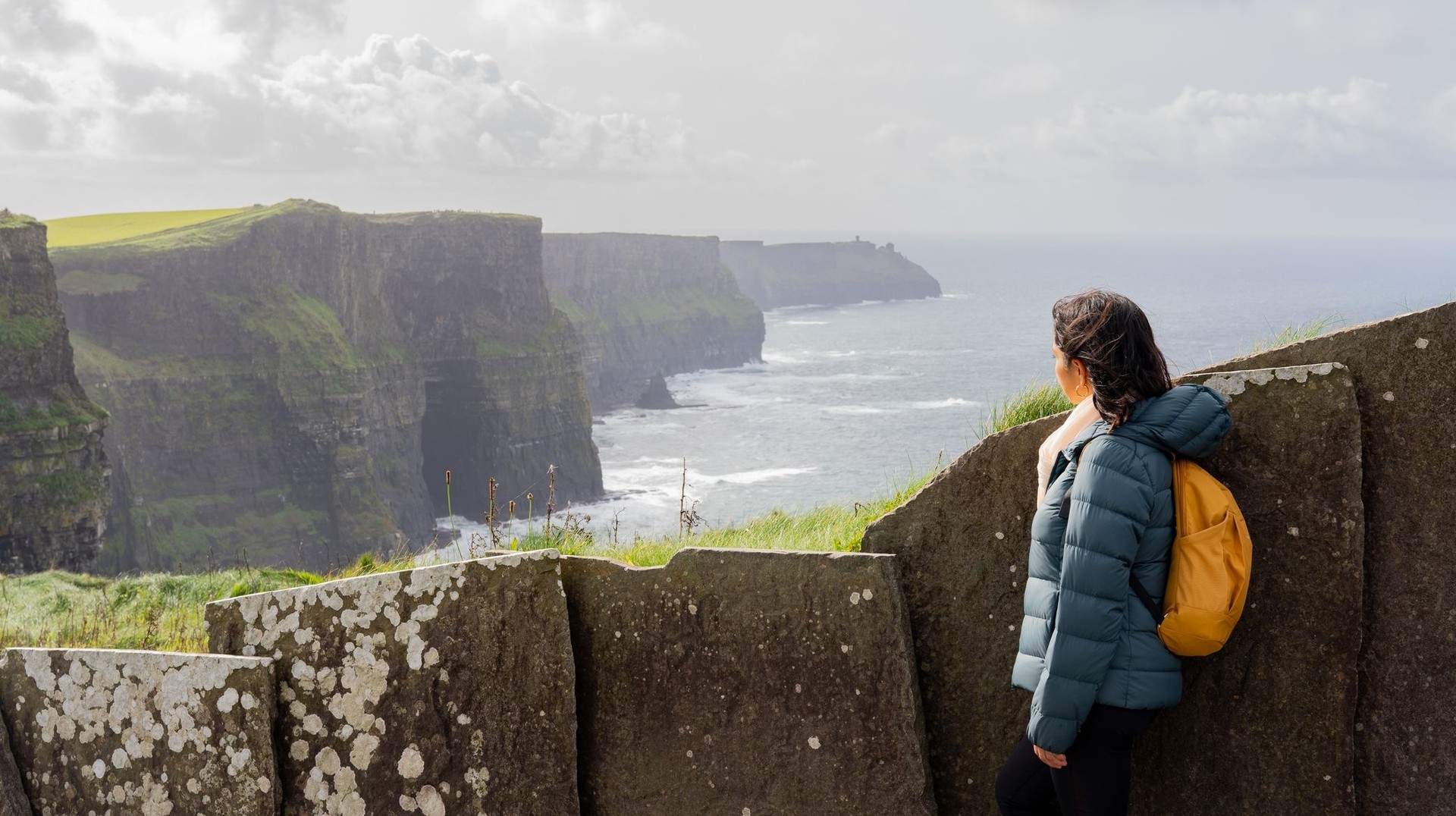 Stand in awe at Moher's Cliffs during your 6 days in Ireland, where stunning views and dramatic scenery create an unforgettable experience. A tourist woman enjoying the view from Moher's Cliff during her 6 days in Ireland.