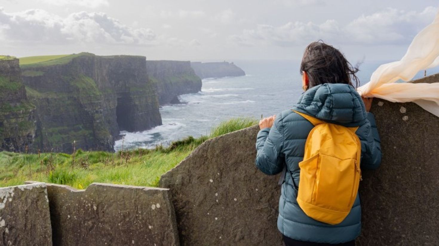 A young woman looking at the beauty of Cliffs of Moher.