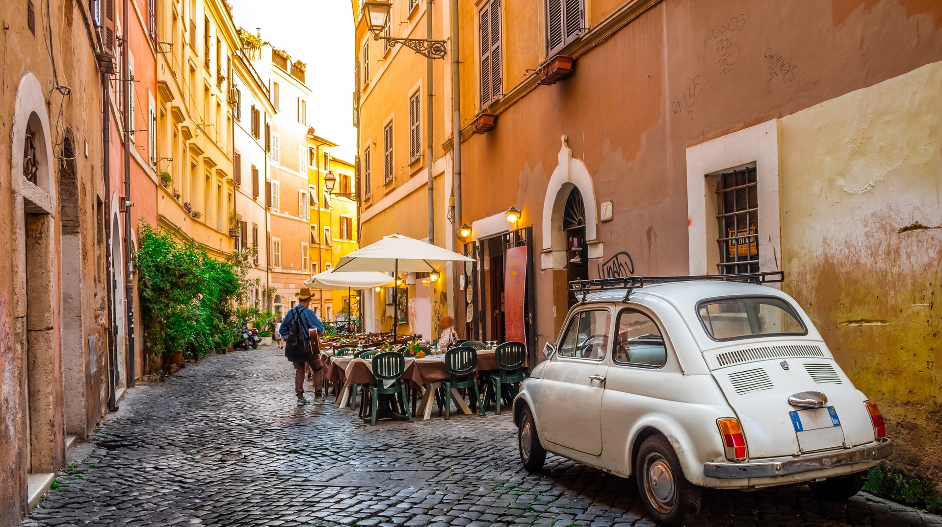 Trastevere has narrow cobblestone streets and trattorias that make it an ideal destination for a romantic trip in Rome, Italy. A narrow street in Trastevere, Italy with a lovely Italian restaurant.