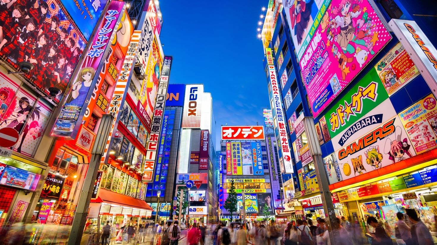 Crowds pass below colorful signs in Tokyo
