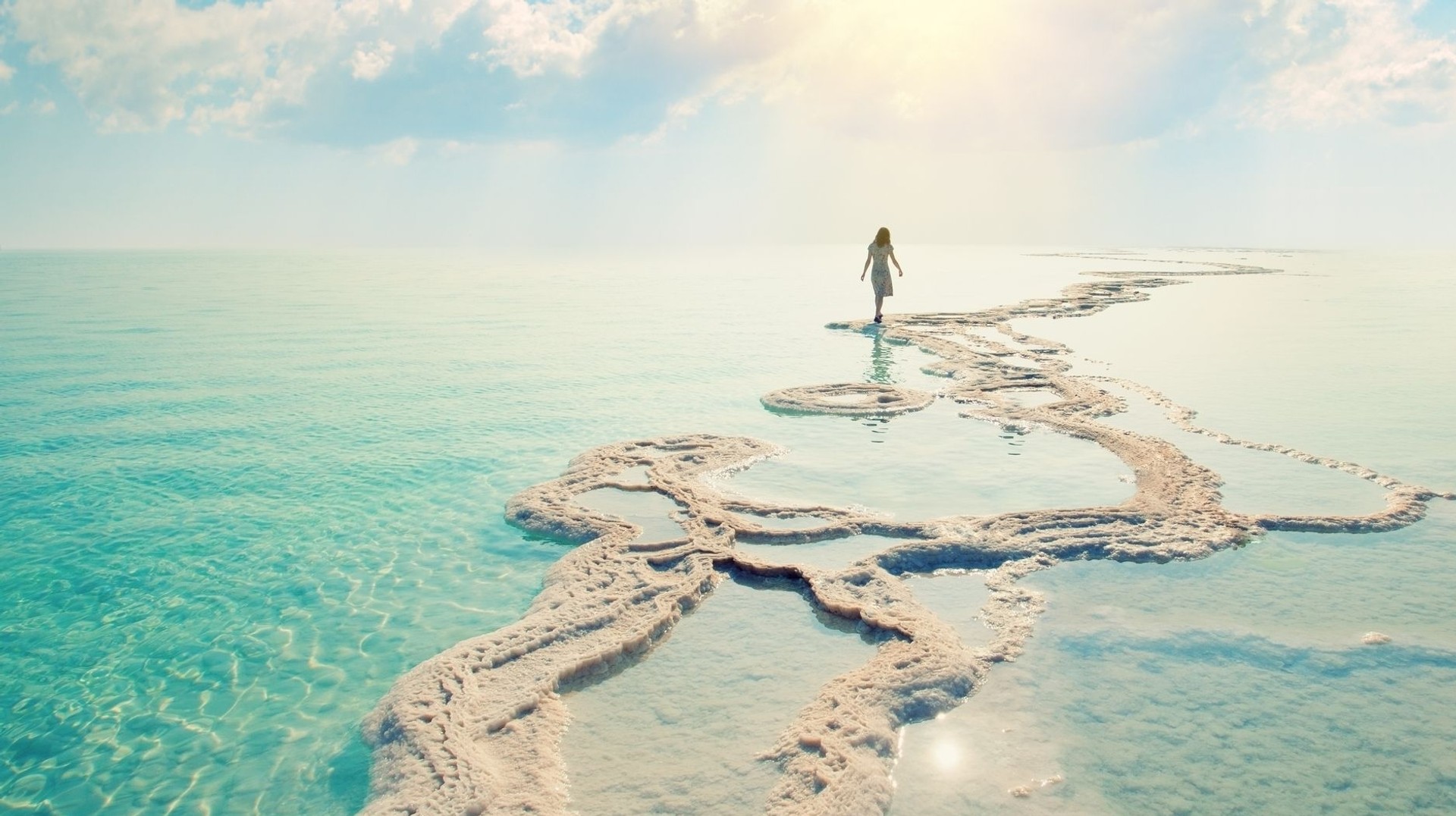 A young woman walking on the Dead Sea salt shores during sunrise on her 8 days in Jordan.
