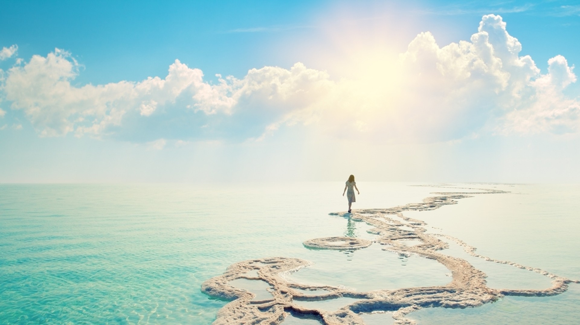 Visit Jordan in October, where sunny weather makes it an ideal time for a pleasant and relaxing holiday. A girl walking along the Dead Sea shore at sunrise in Jordan in October.