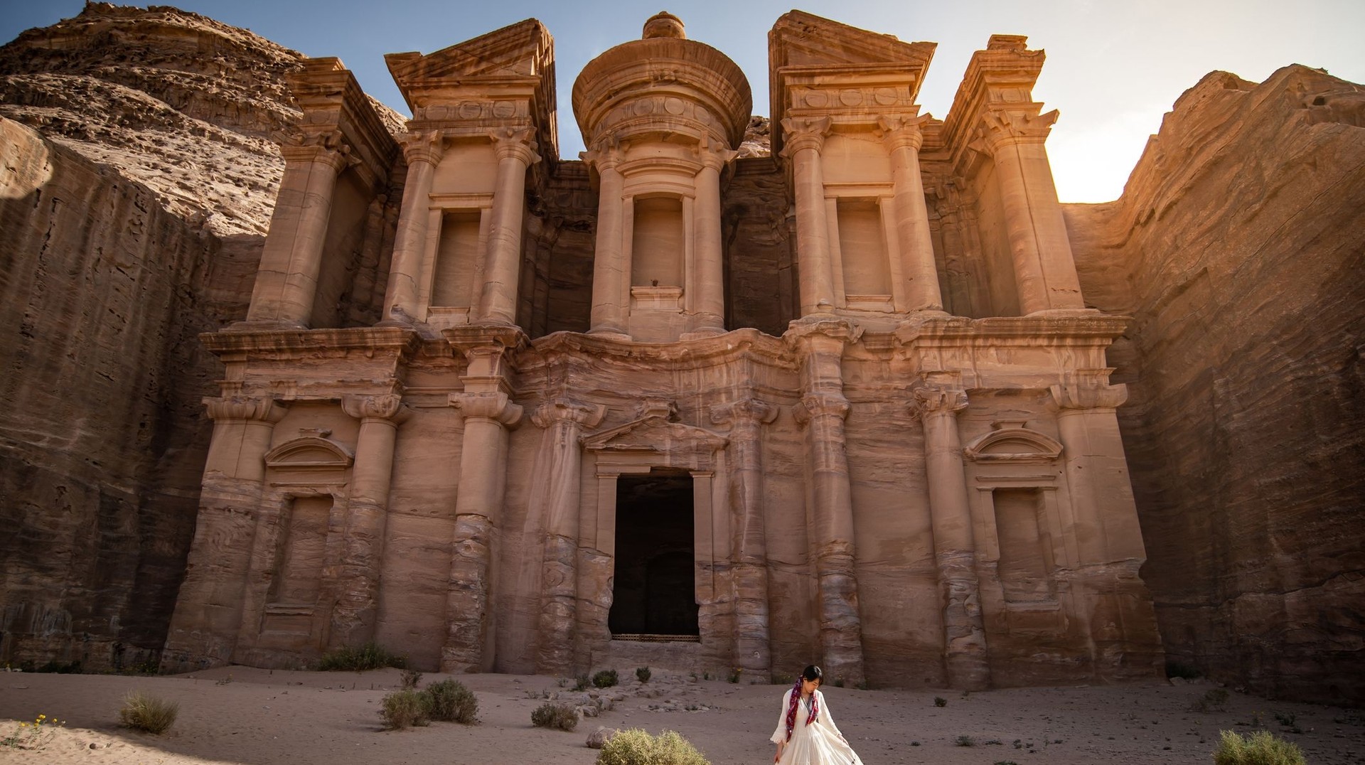 A woman in white dress standing at Ad Deir in Petra during her one week in Jordan.