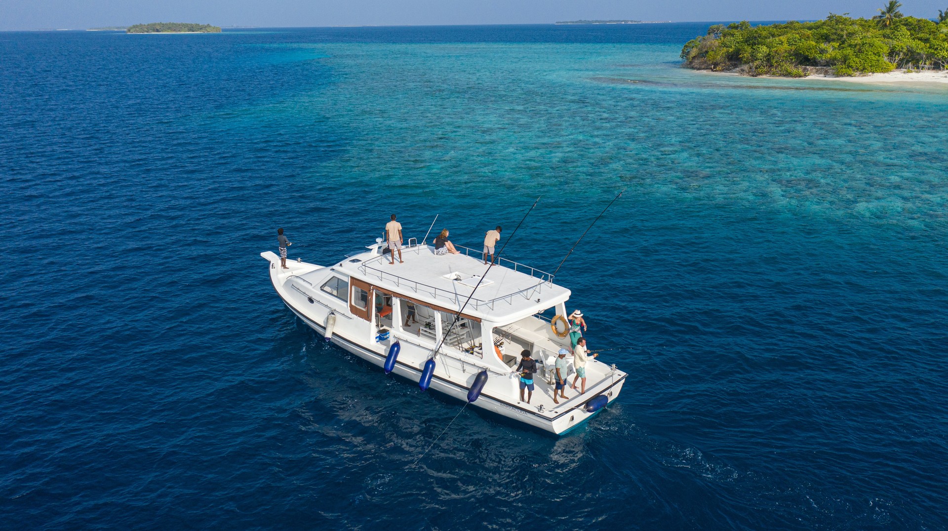 Feel the serene thrill of fishing in the calm waters of the Maldives in December while cruising on a luxurious yacht. Tourists fishing in Raa Atol while on a yacht in the Maldives in December.