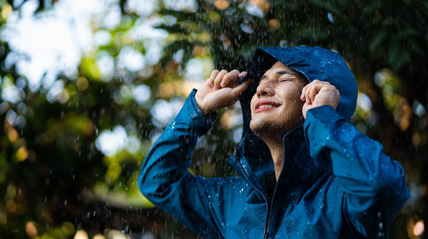 Young Asian man in raincoat in the outdoor with rain