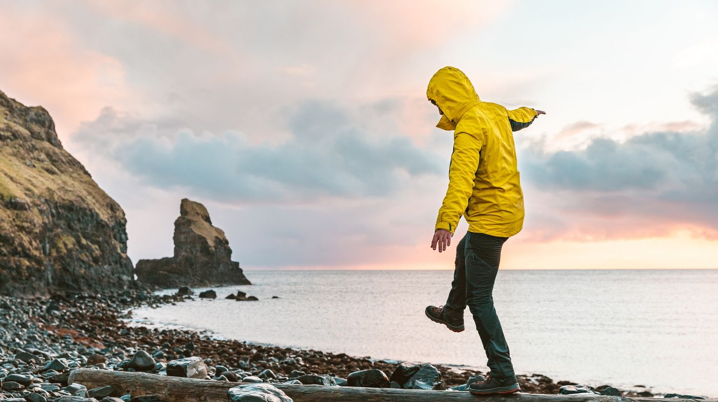Man hanging in the balance over a log at seaside