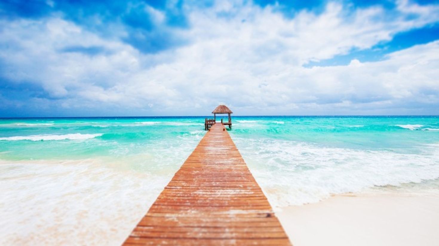 A long deck and a small structure at the end at a beach in Mexico.