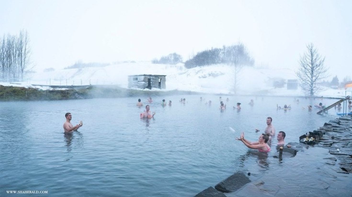Tourists swimming in the waters of Secret Lagoon.