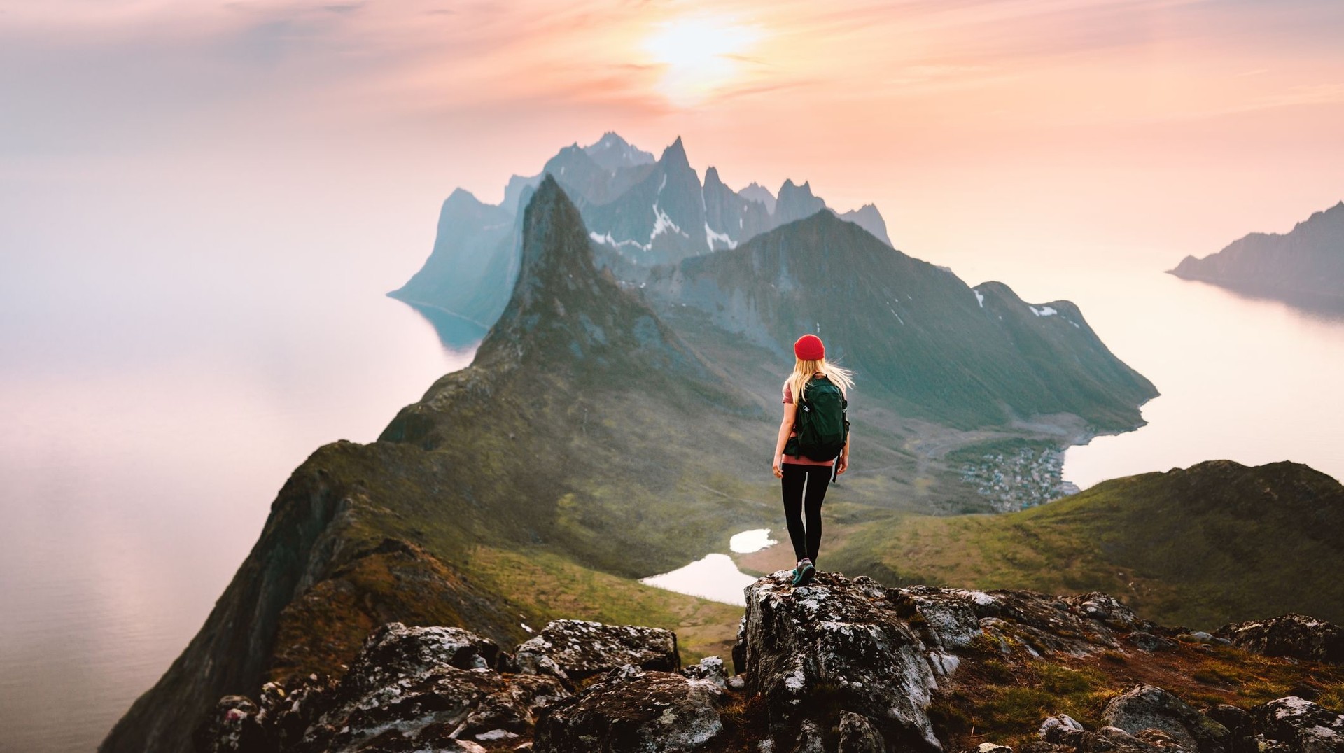 A woman hiker solo in the mountains enjoying the sunset view on Senja Island on her 12 days in Norway.