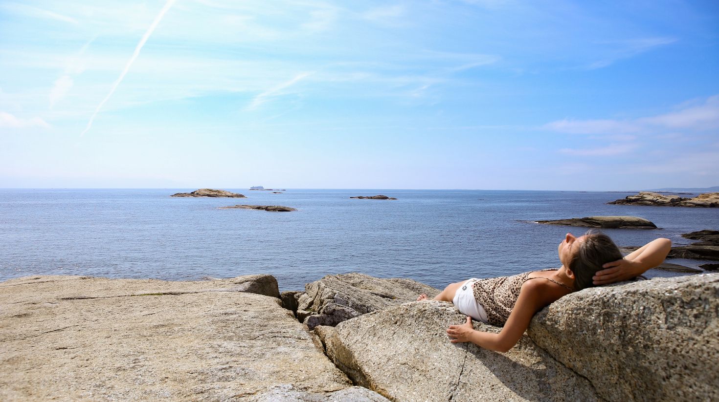 A woman sunbathing in the beach of Norway.