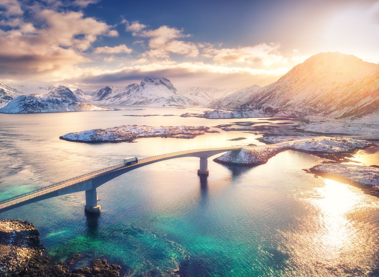 Aerial view of bridge showing sea and snowy mountains in Lofoten Islands