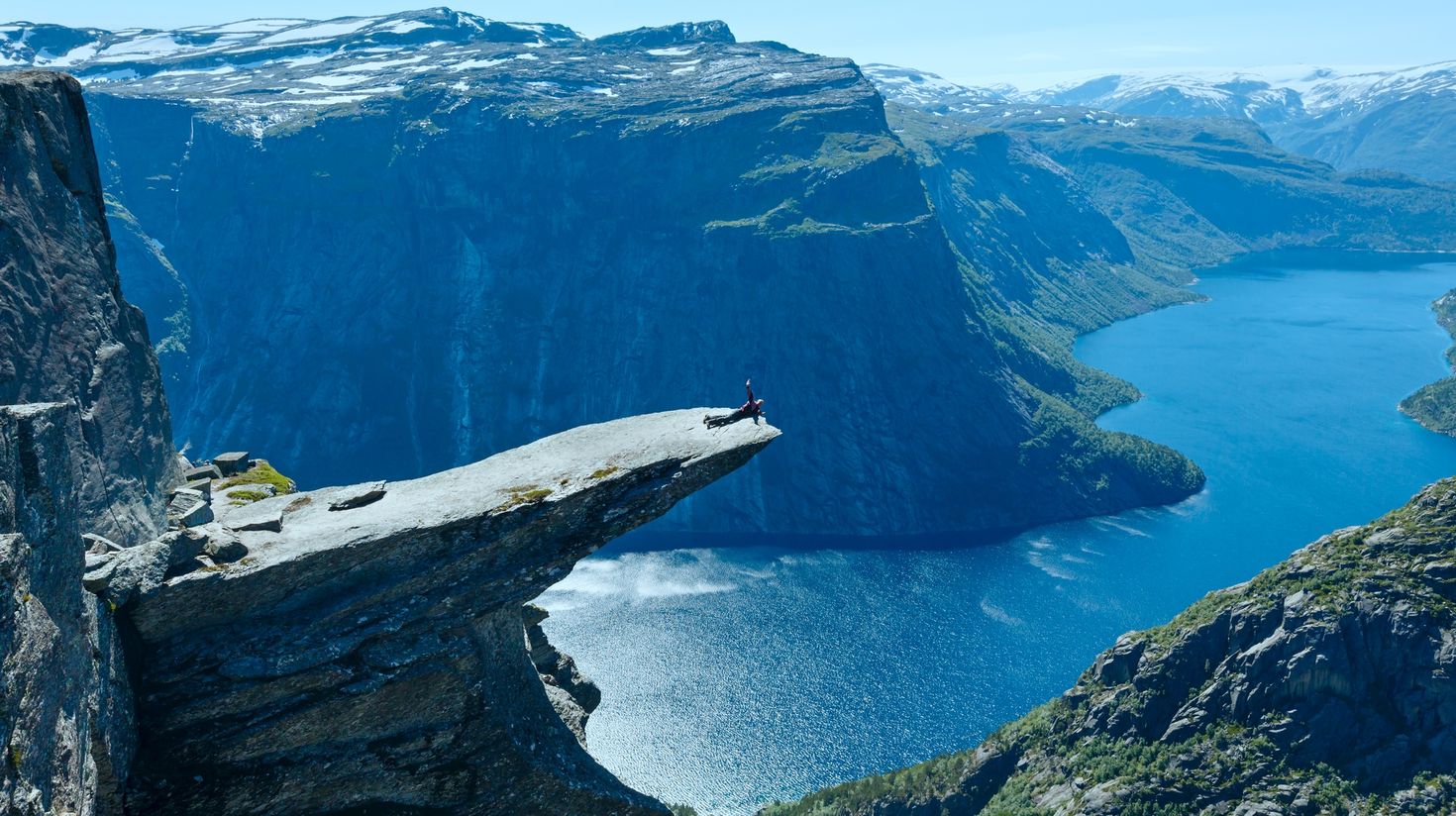 Trolltunga summer view on Norway tour and man on rocks edge.