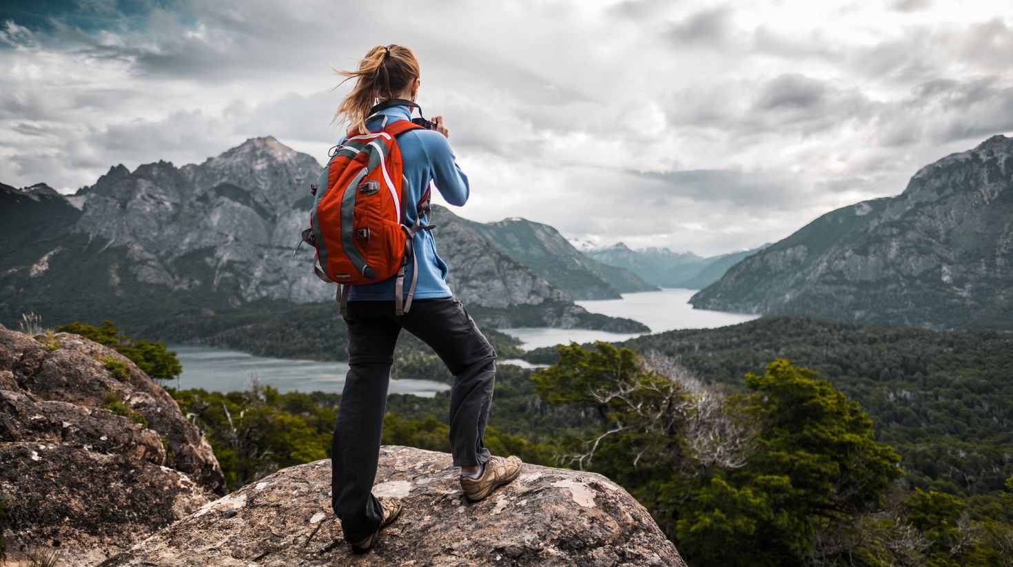 A woman tourist taking pictures of the valley from top in Patagonia.