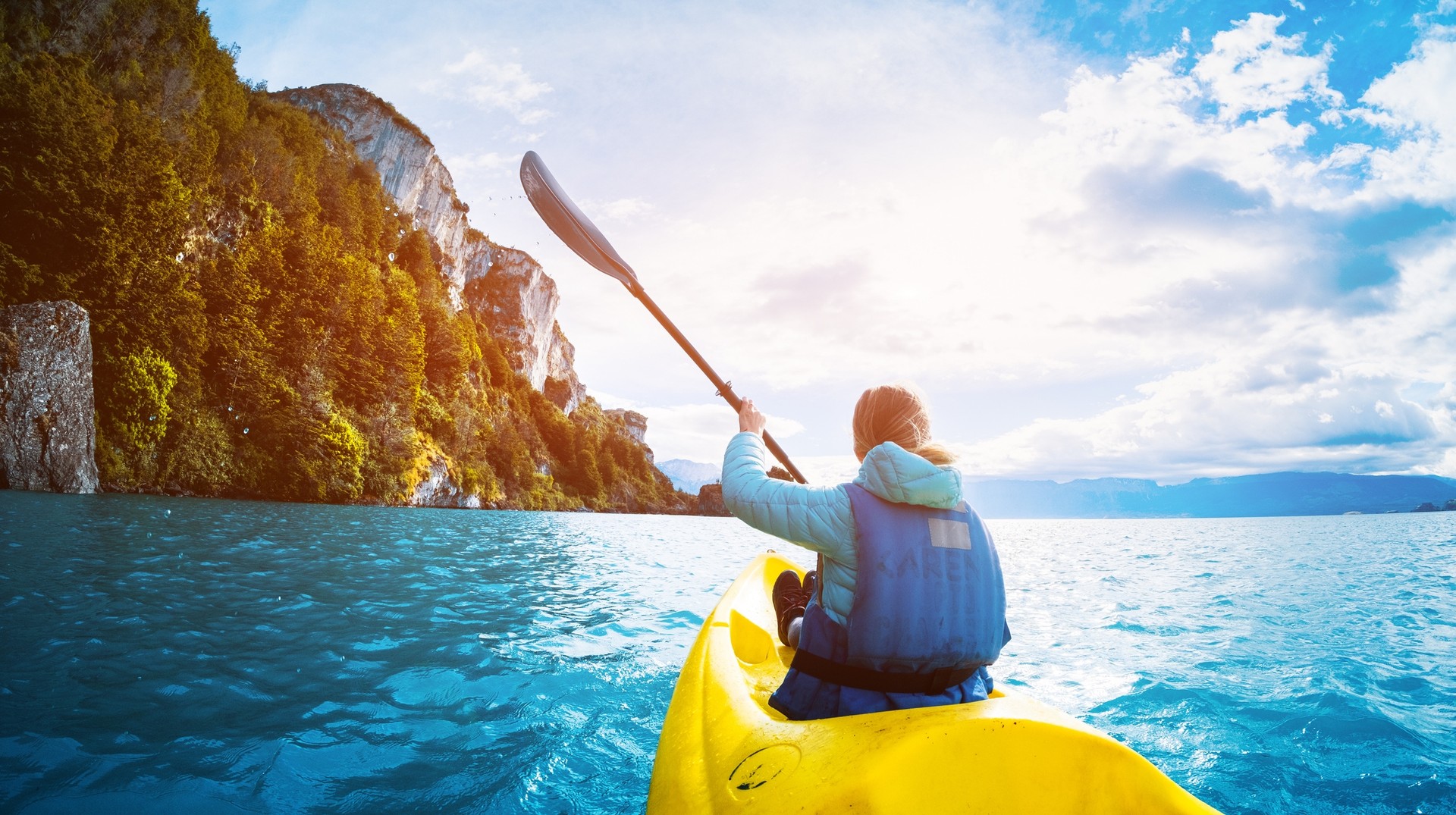 Enjoy a sea kayaking experience in the fjord during your trip to Patagonia in October. A woman paddles kayak on the lake in Patagonia in October.