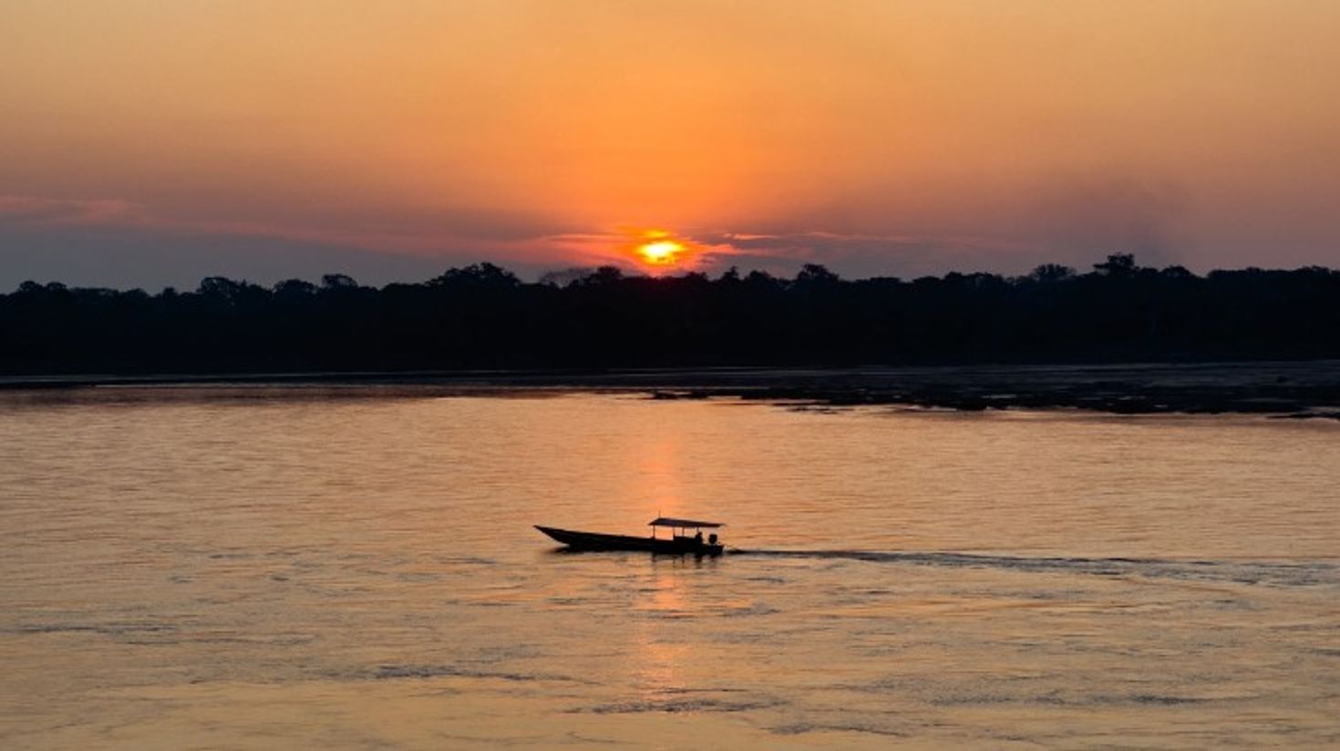 A boat in the Madre de Dios River during the sunset in Puerto Maldonado.