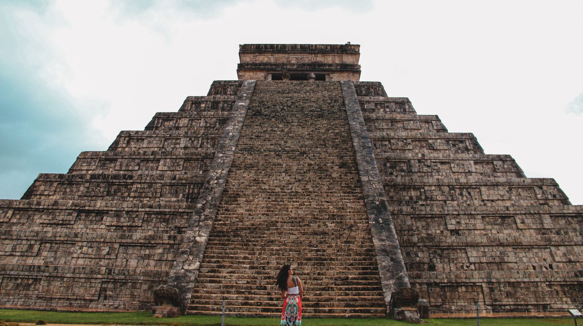 Marvel at the majestic pyramid of Chichen Itza, a crown jewel among the top places to visit in Mexico, and uncover the mysteries of this ancient wonder. A girl standing in front of a pyramid in the ancient city of Chichen Itza, one of the top places to visit in Mexico.