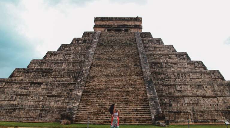 A girl standing in front of a pyramid in the ancient city of Chichen Itza, one of the top places to visit in Mexico.
