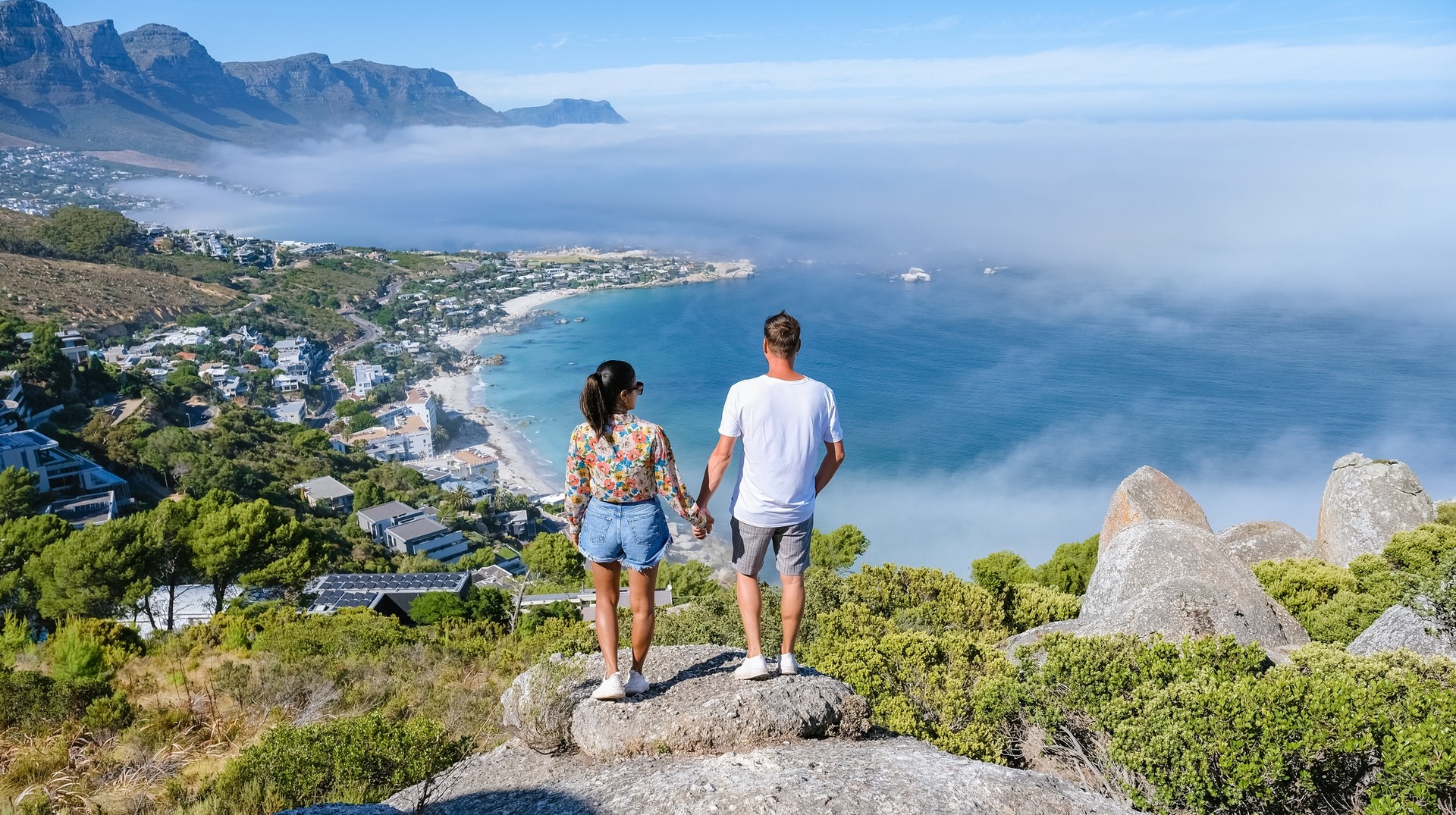 Discover the vibrant beauty of Cape Town, one of the top places to visit in South Africa, where stunning landscapes, rich culture, and endless adventures await! A couple holding hands and enjoying the view of Cape Town, one of the best places to visit in South Africa, from the Rock Viewpoint.