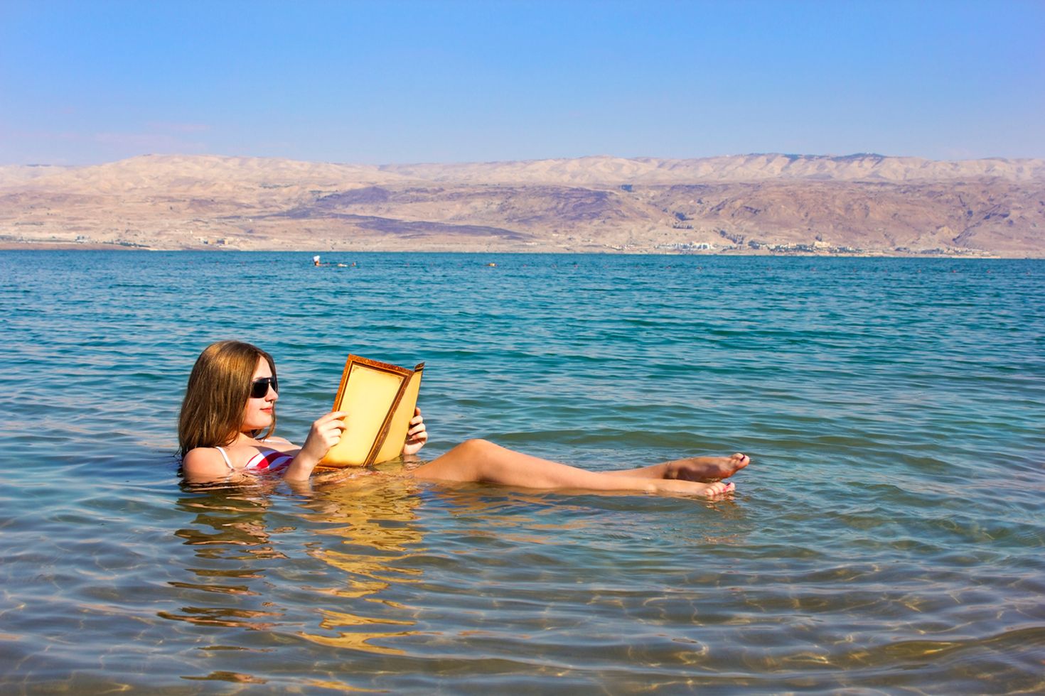 A girl reading a book while floating in the dead sea.