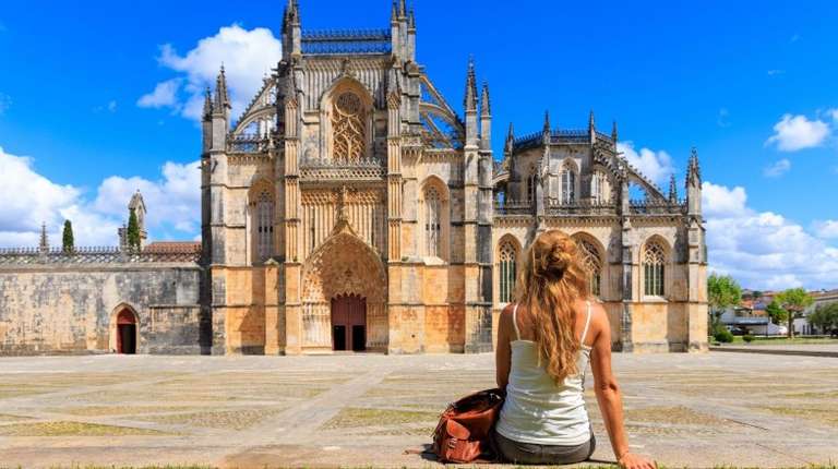 A girl in front of Batalha Monastery on a clear day during her 13 days in Portugal.