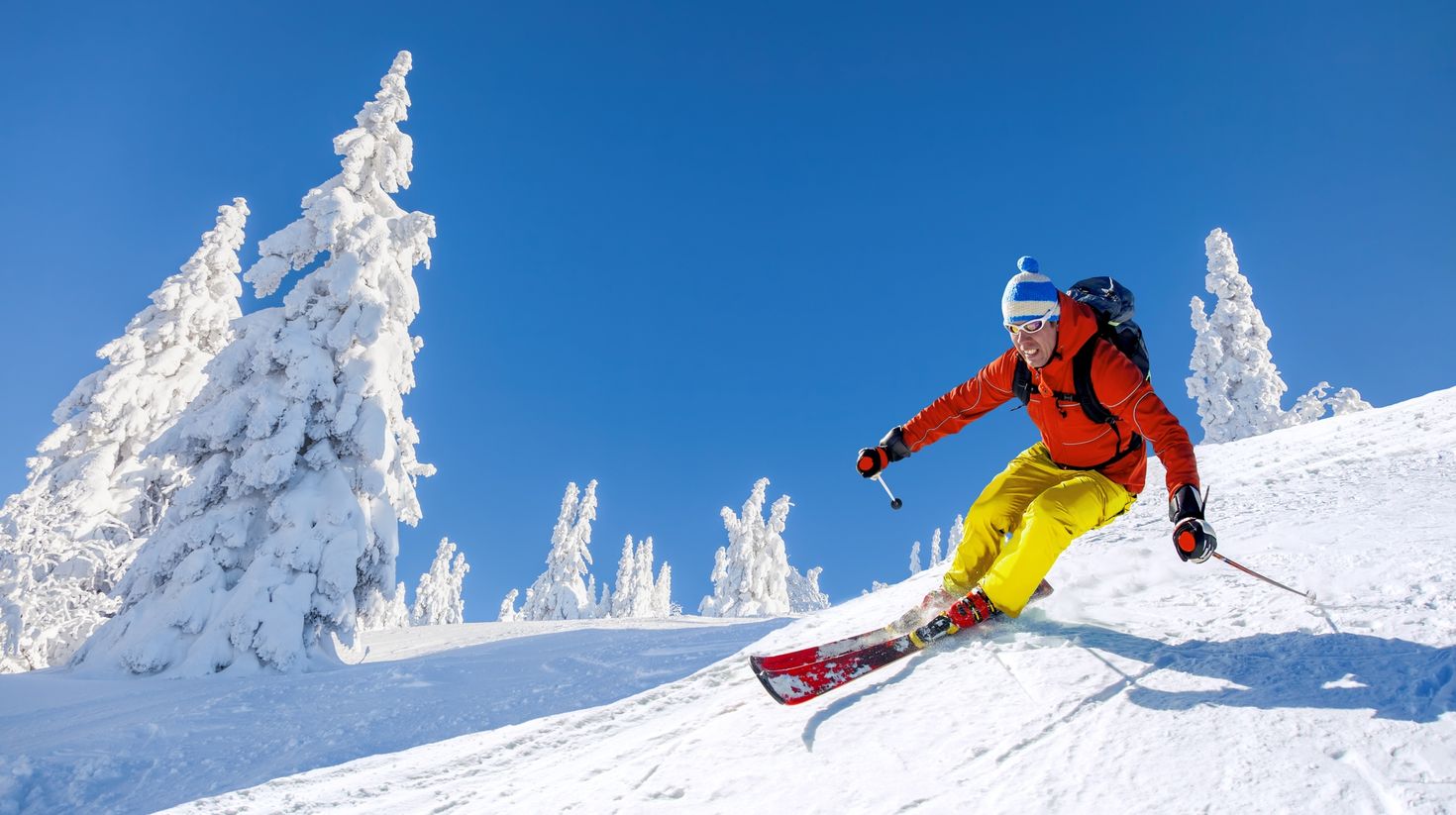 Skier skiing downhill in high mountains against blue sky