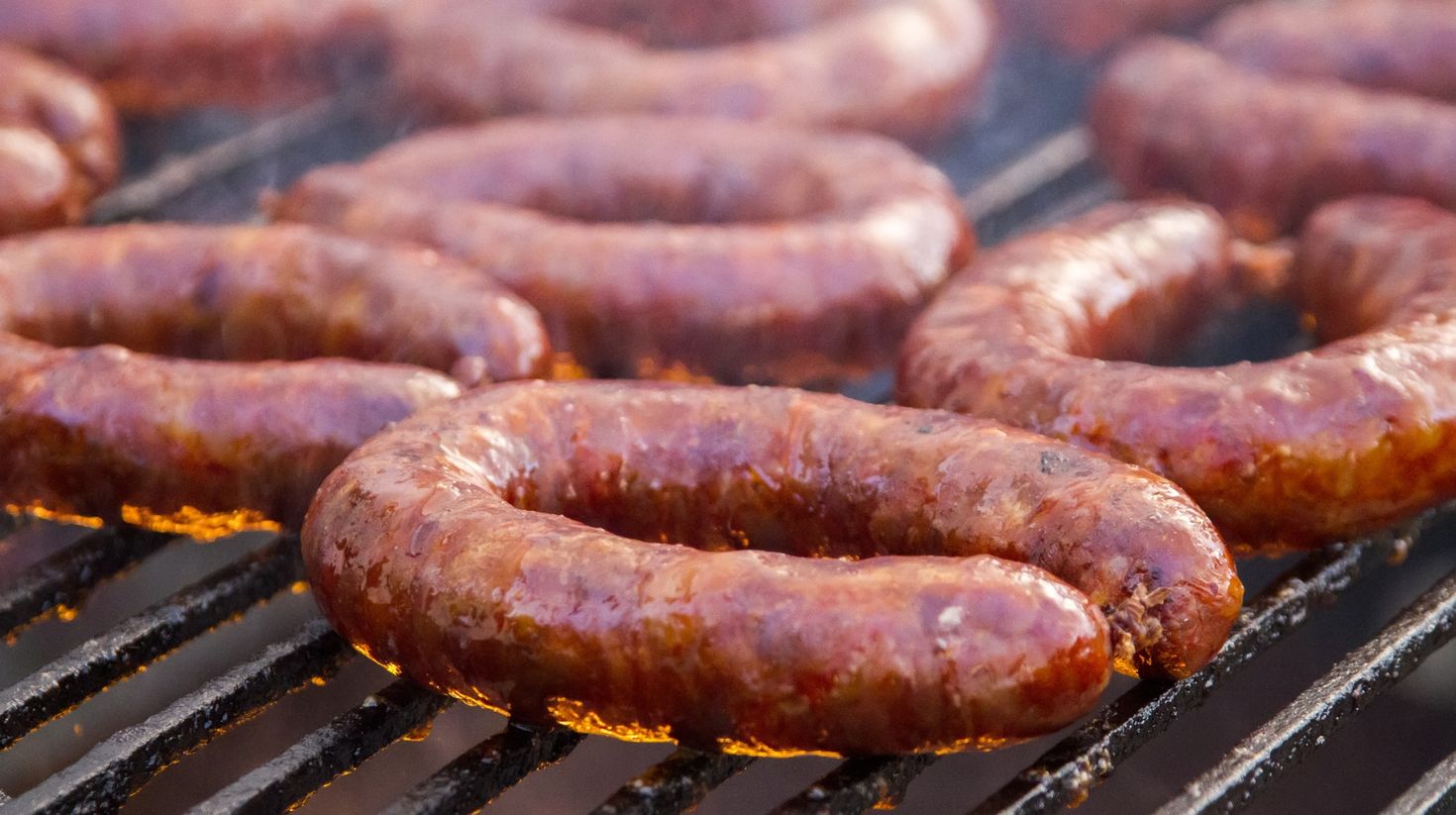 Close up view of many Portuguese chorizos on a barbecue.
