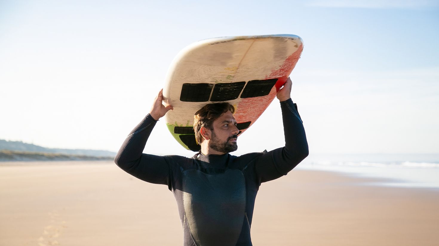 surfer holding surfboard on head