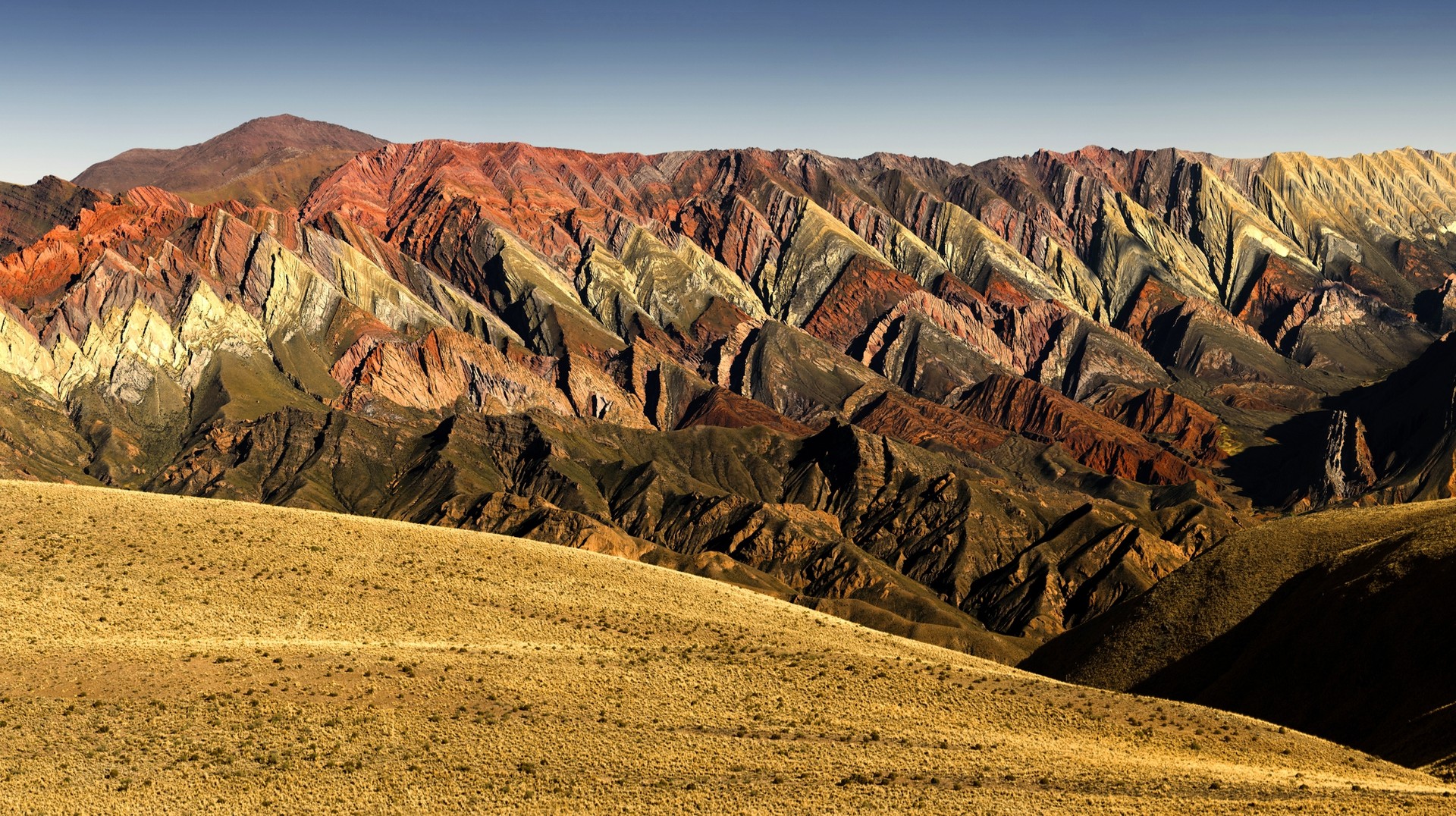 The mountains of Quebrada de Humahuaca flaunt waves of colors, ranging from rich bands of red, vibrant pink, creamy white, and patches of green.