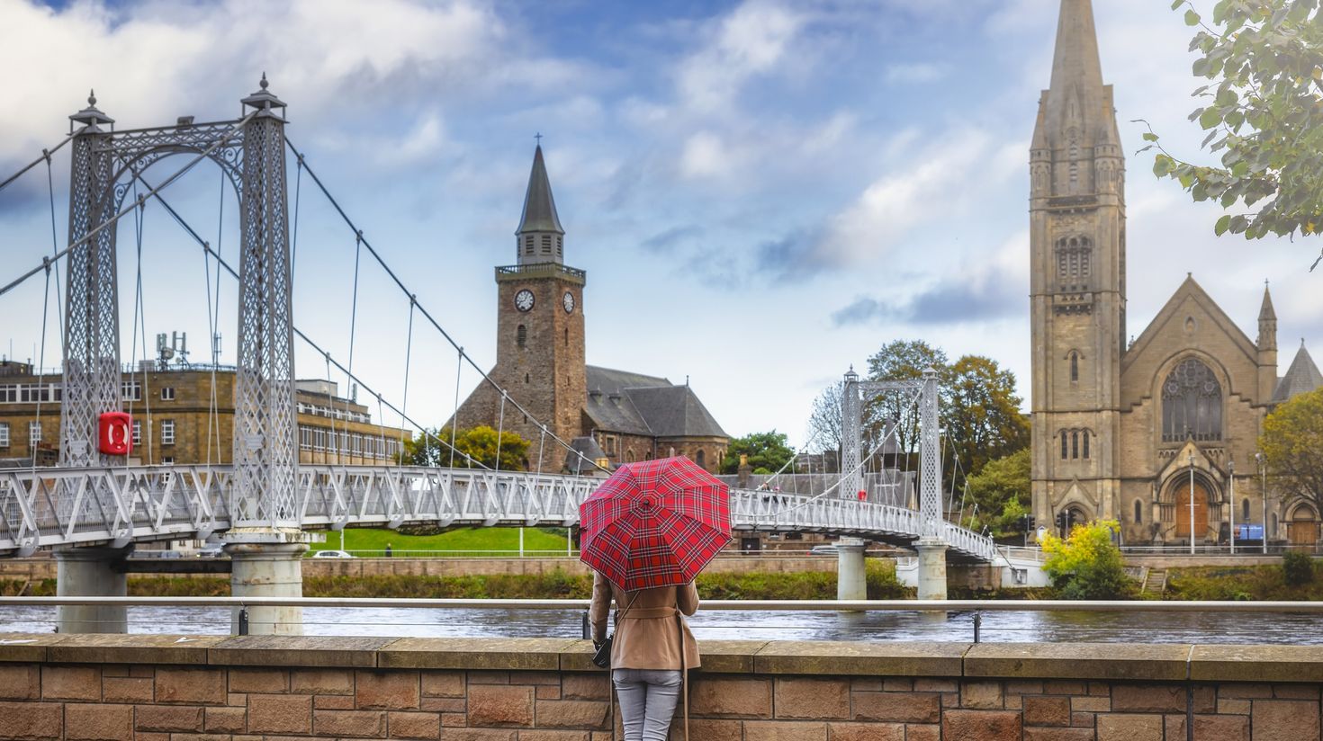 A tourist with a scottish pattern umbrella enjoys the view to the cityscape