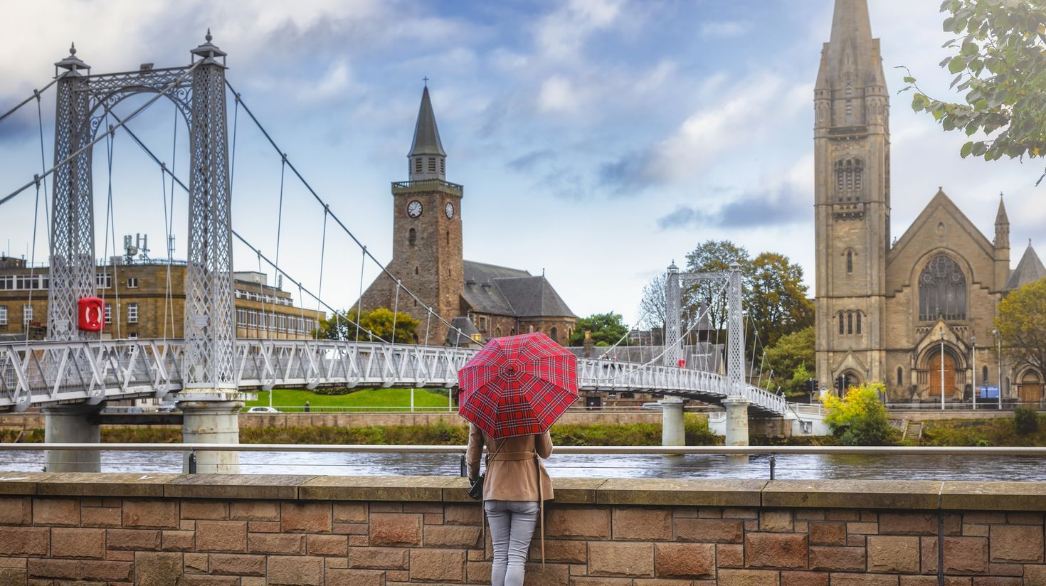 A tourist with umbrella enjoys the view in Scotland in September