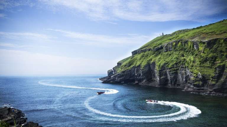 Two boats making patterns on a clear day off the shores of Jeju Island in South Korea in August.