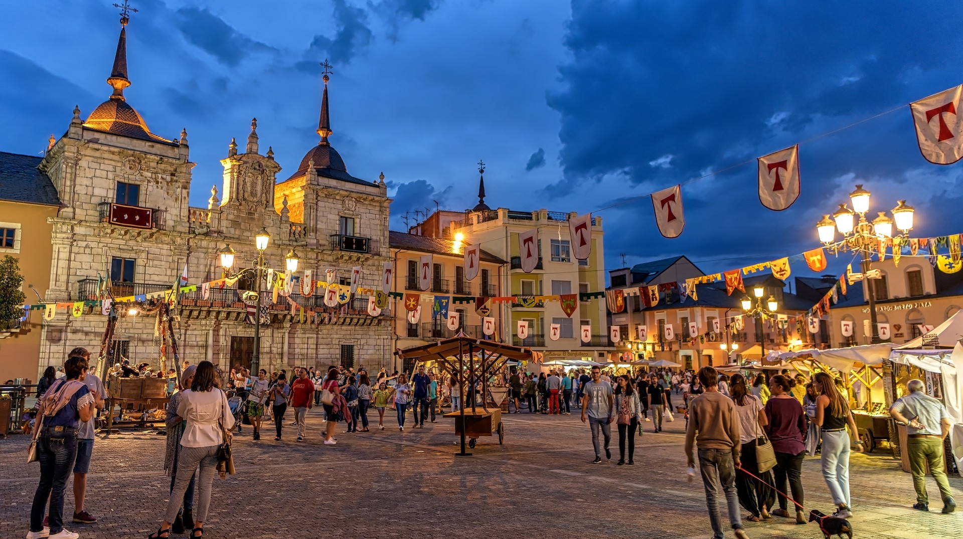 Spanish cities in spring are bustling with locals and tourists enjoying the vibrant culture and lifestyle of Spain in March. Night view of the Medieval Fair at City Hall plaza, northern Spain in March