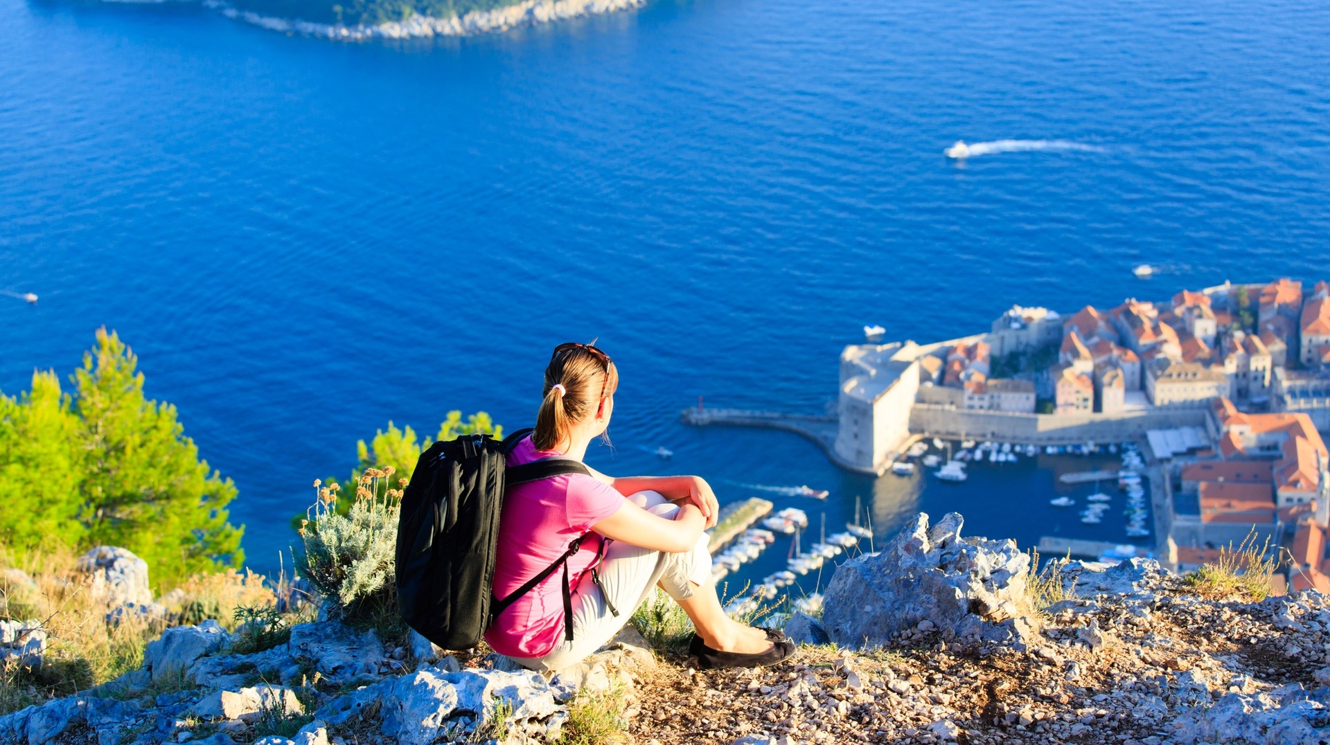 Experience the best of summer in Croatia as you embark on thrilling hikes and immerse yourself in the awe-inspiring beauty of its landscapes. A tourist hiker at the top of the mountain admiring the view during summer.