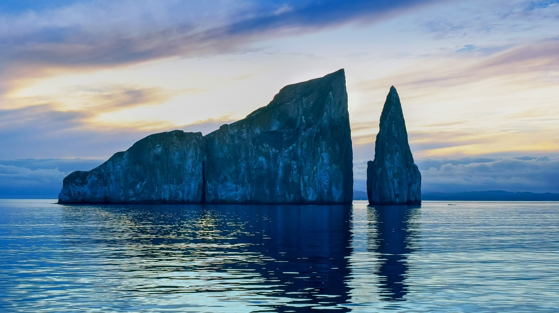 Watch the sun rise at the Galapagos Islands on a boat in the summer. View of Leon Dormido during sunrise during summer in Ecuador.