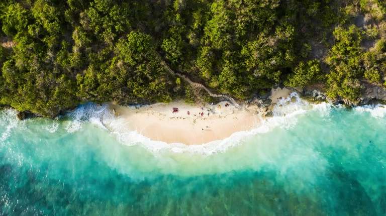 An ariel view of a small beach with tourists in summer in Indonesia.